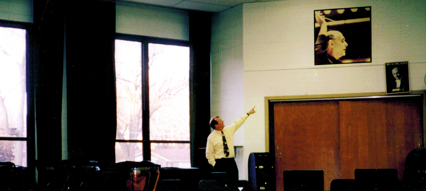 Dr. Moss revisists the York HS band room prior to demolition. Pointing to a signed photo of Georg Solti from Moss's time at York. 